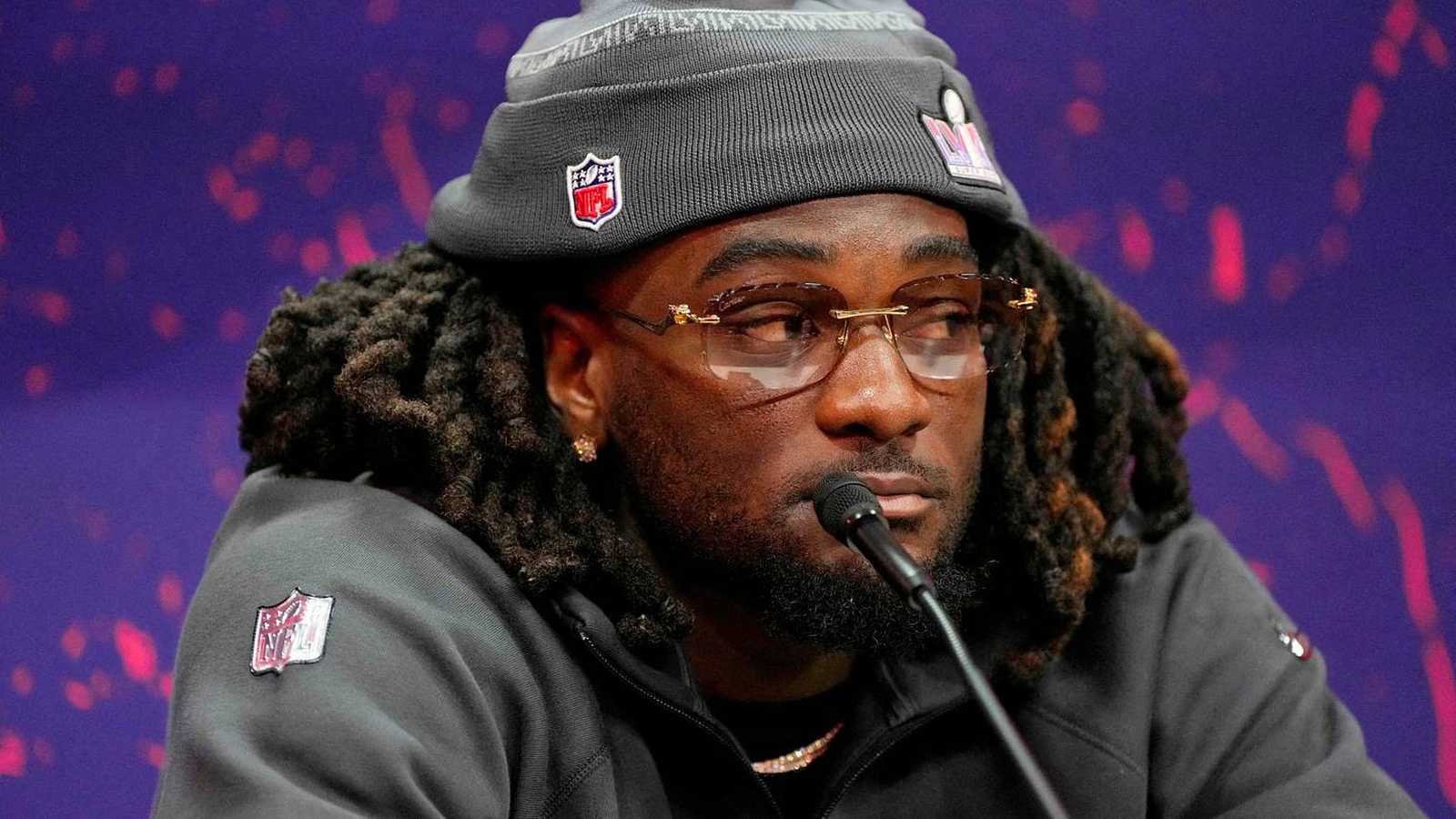 Brandon Aiyuk wearing a beanie and glasses speaking at an NFL press conference