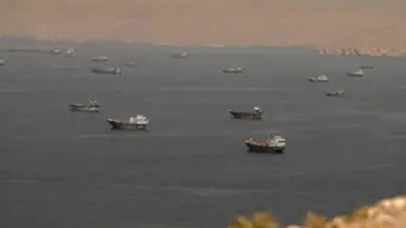 Multiple commercial cargo ships navigating the waters of the Strait of Hormuz