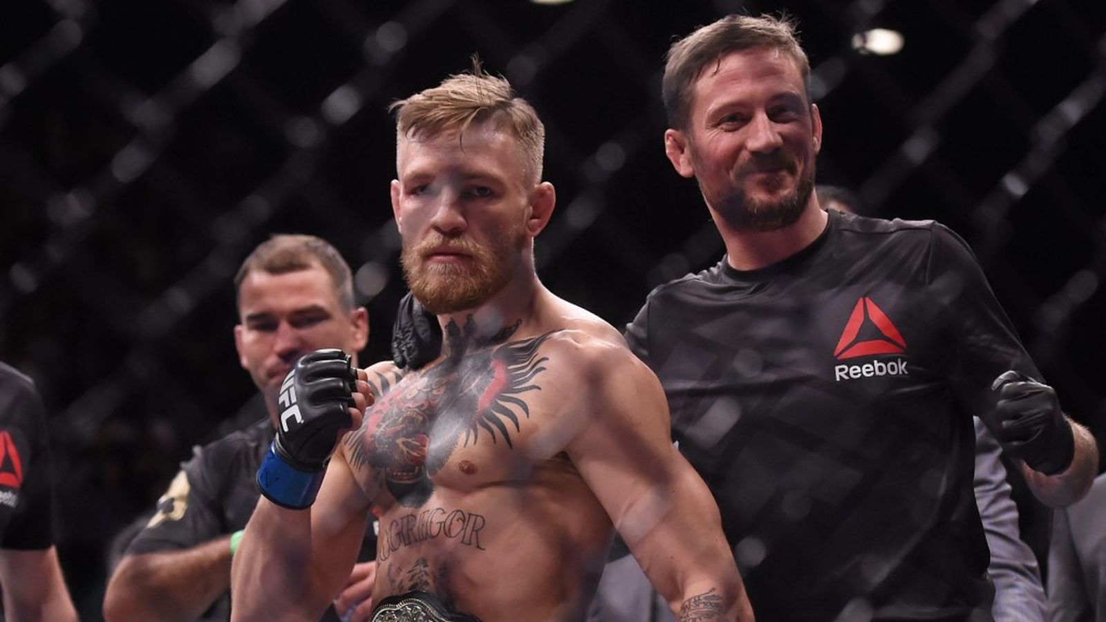 Conor McGregor standing in the octagon with his coach John Kavanagh after a fight