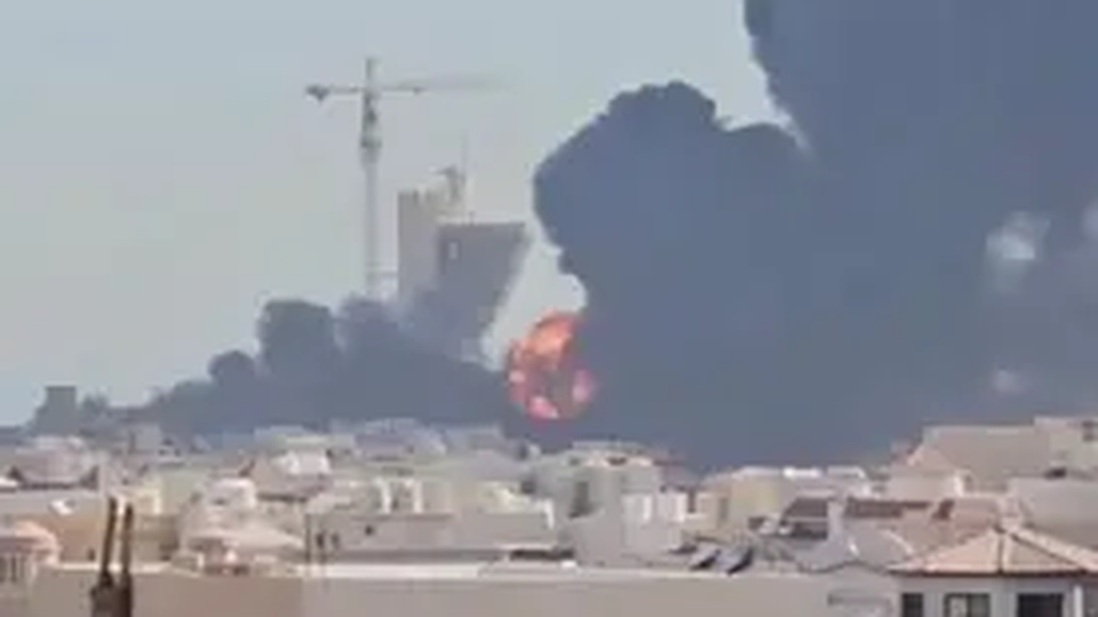 A large explosion and plume of black smoke rising over an urban landscape