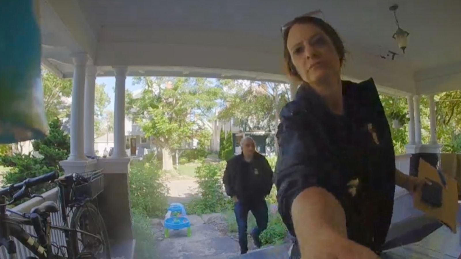 A federal agent reaches toward a doorbell camera while another stands in the background