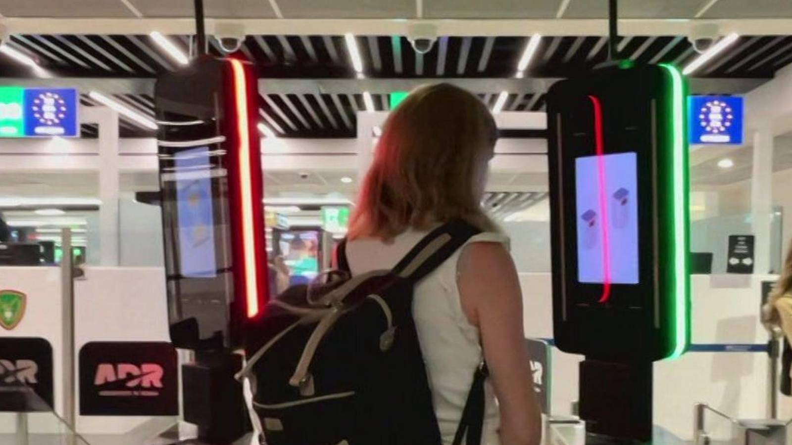 A traveler standing before an automated biometric kiosk at an airport border control point