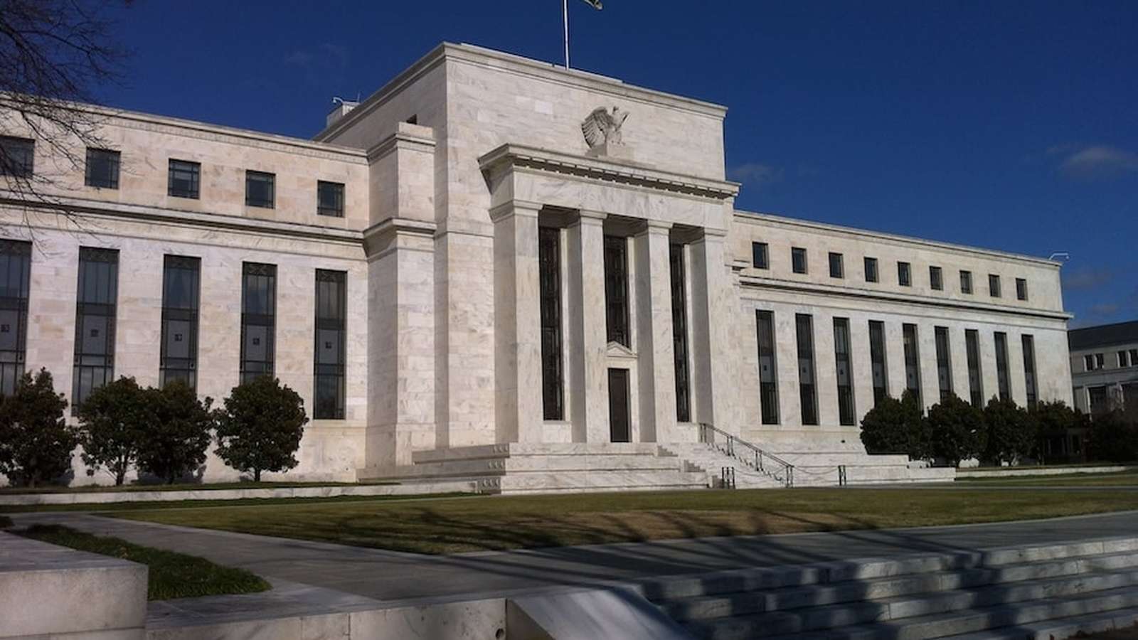The exterior of the marble Federal Reserve building under a clear blue sky