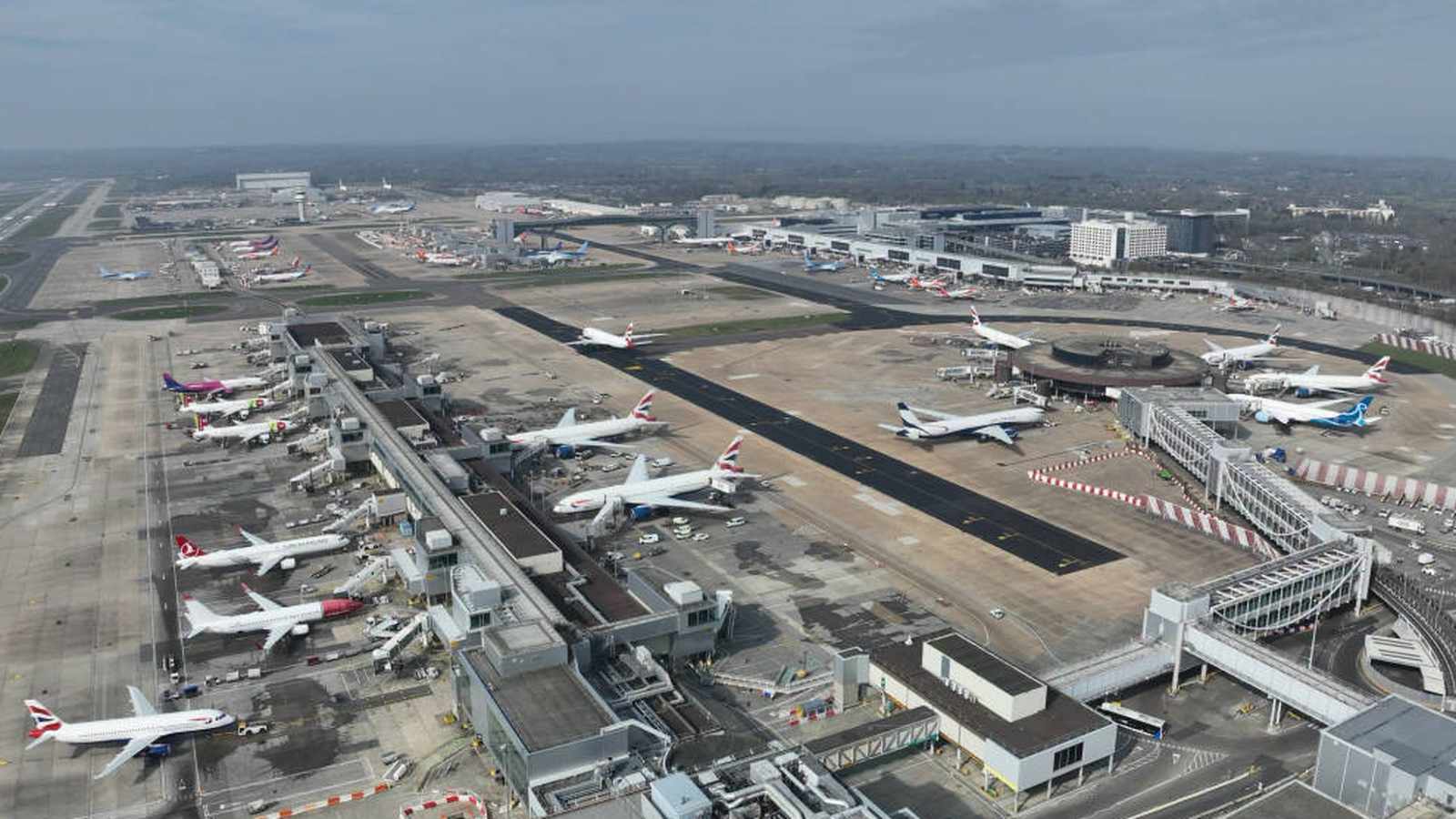 An aerial view of London Gatwick Airport with multiple commercial airplanes parked at gates