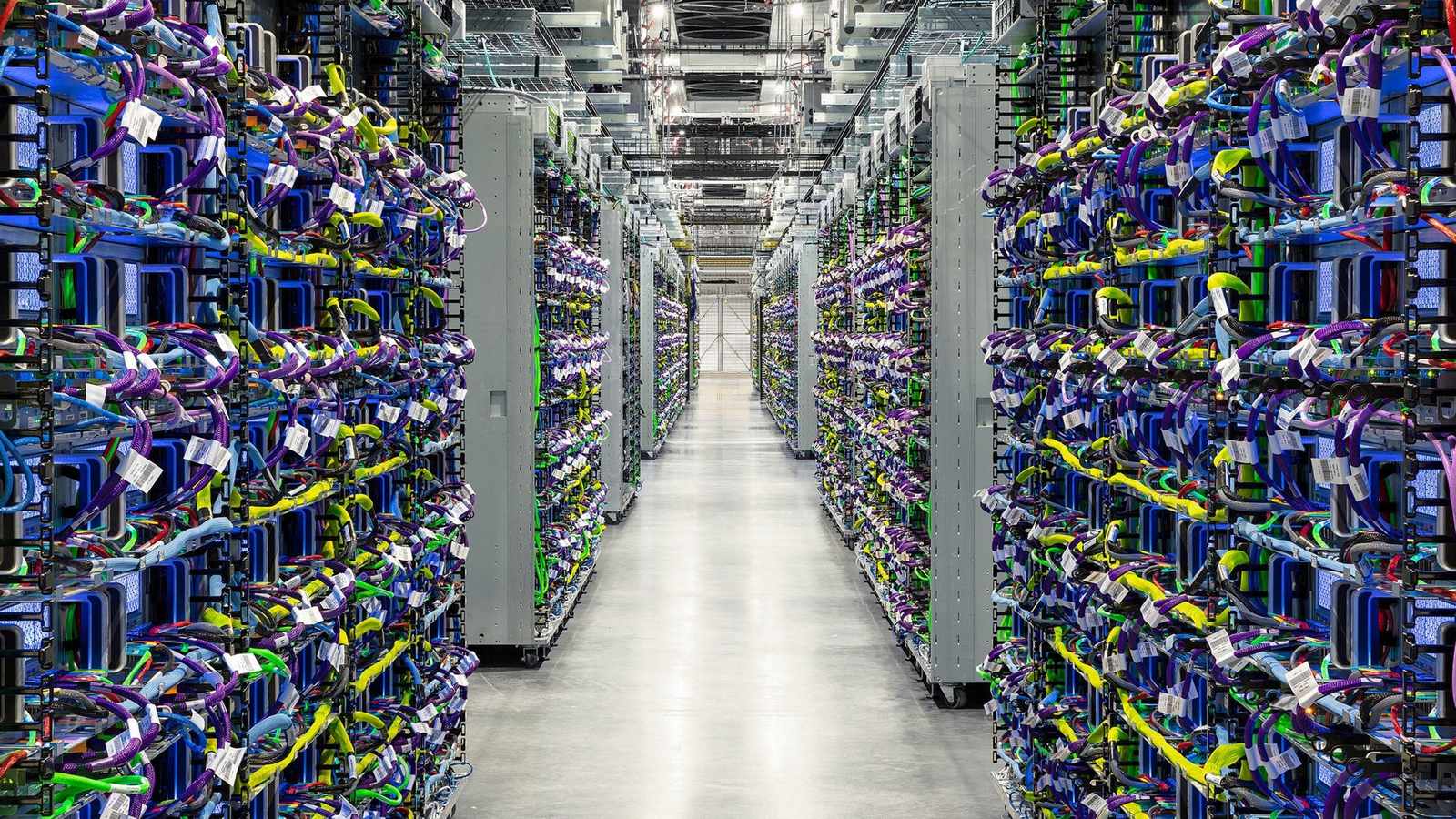 Rows of server racks with colorful networking cables inside a large data center facility