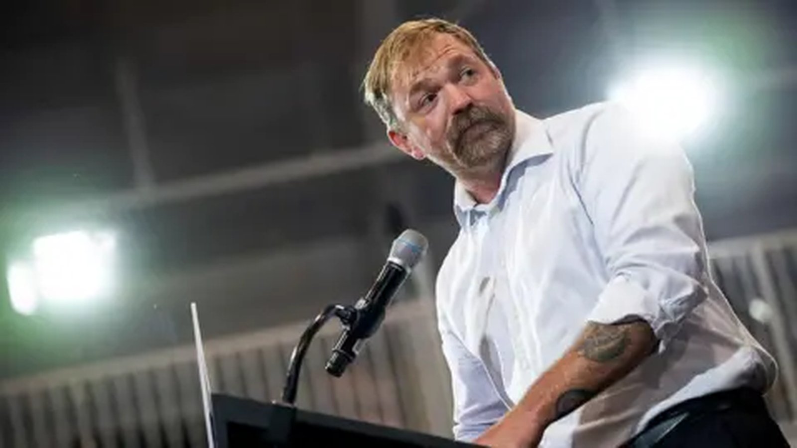 Graham Platner speaking at a podium during a political campaign event in Maine
