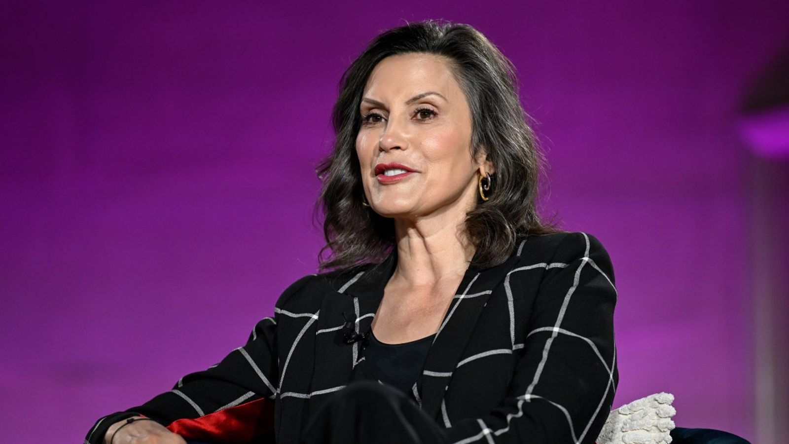 Michigan Governor Gretchen Whitmer speaking at an event wearing a black plaid blazer