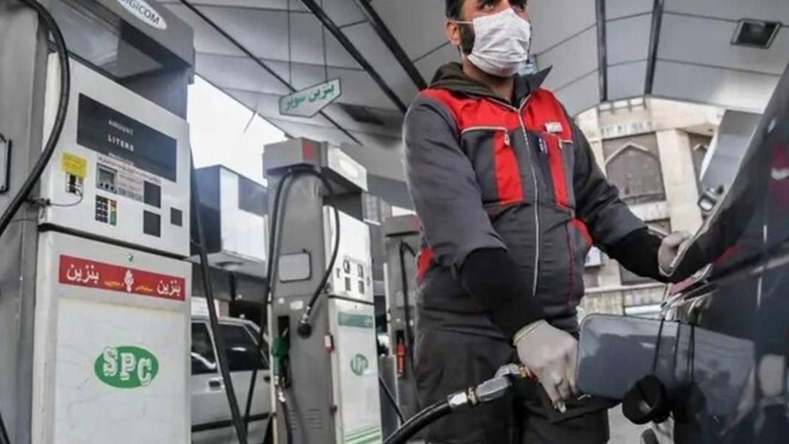 A gas station attendant wearing a face mask fueling a car in Iran