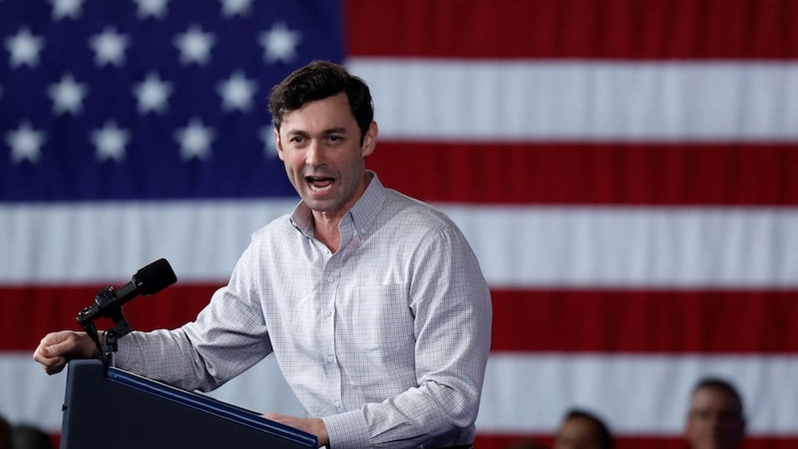 Senator Jon Ossoff speaking passionately at a podium in front of American flag
