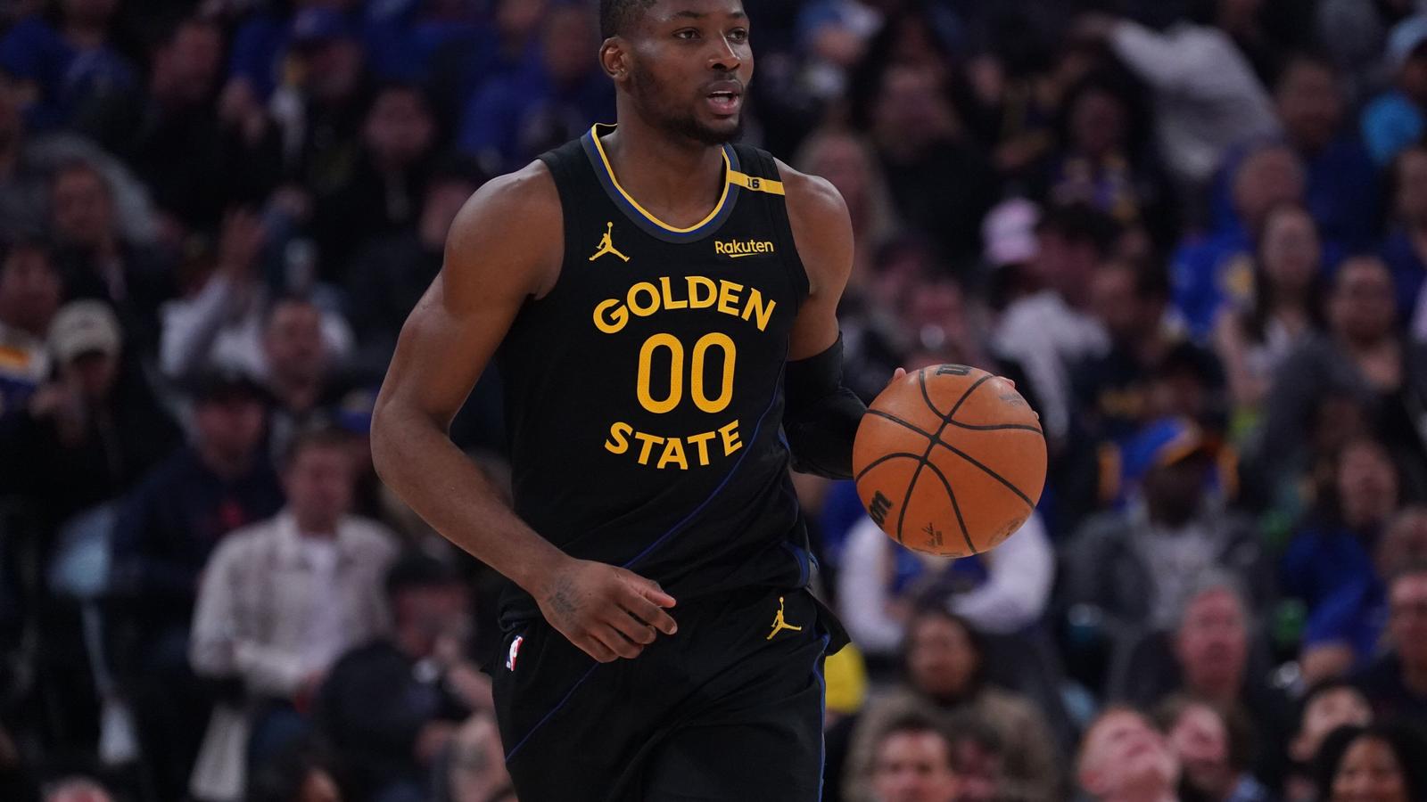 Jonathan Kuminga wearing a black Golden State Warriors jersey dribbling a basketball on court