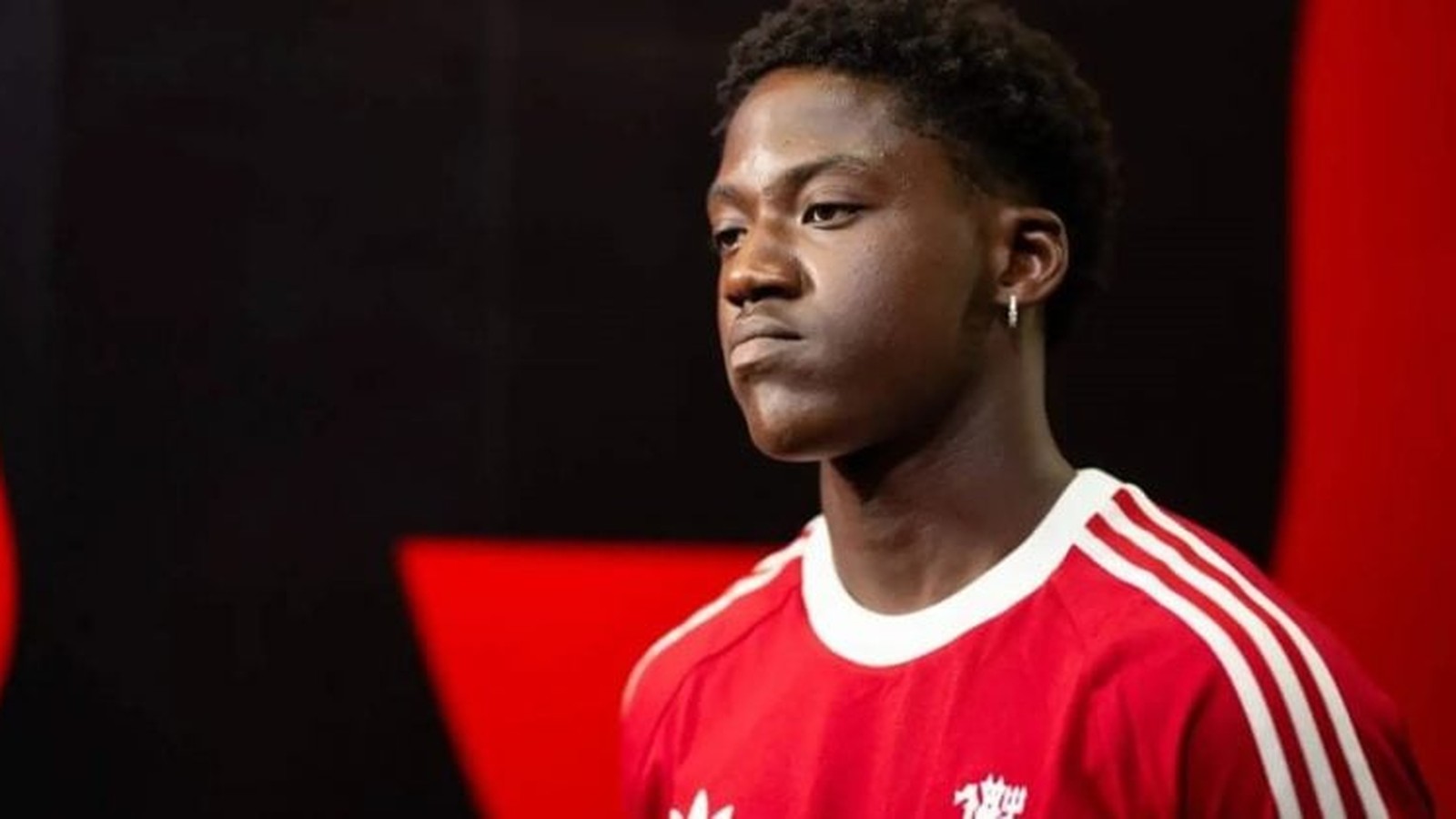 Manchester United midfielder Kobbie Mainoo wearing a red training shirt looking serious