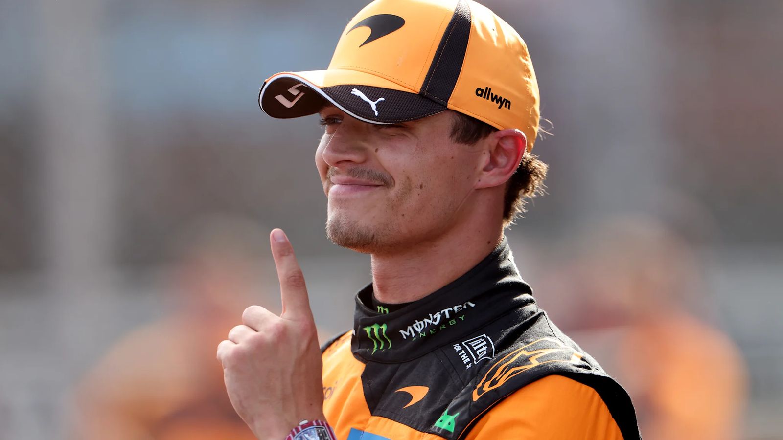 Lando Norris wearing a McLaren team cap and racing suit smiling after qualifying