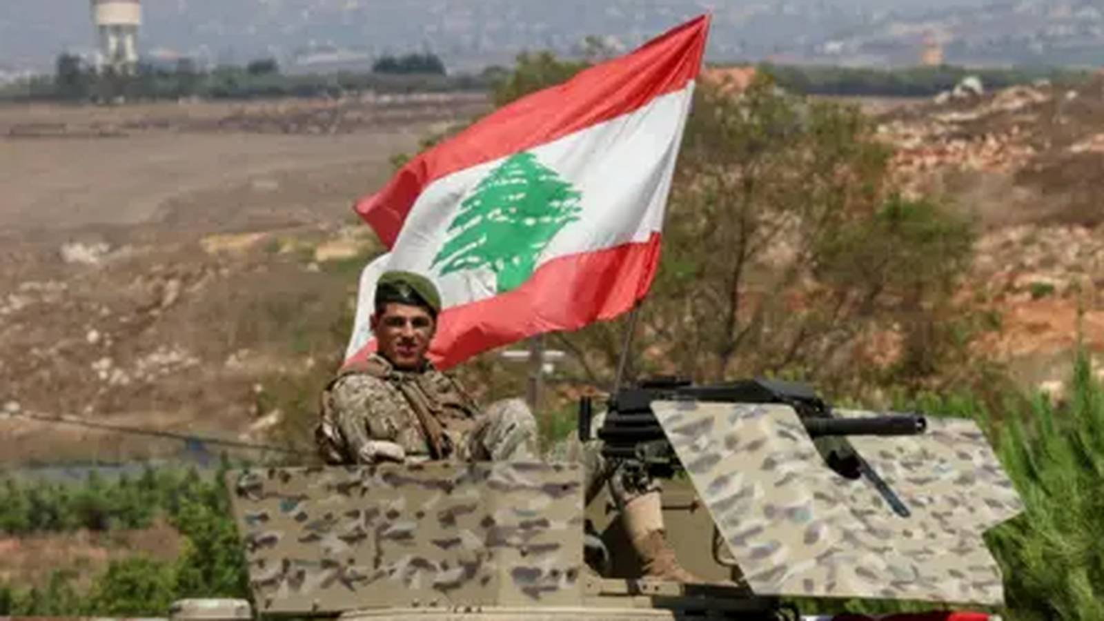 A Lebanese soldier sits atop a military vehicle flying the Lebanese national flag