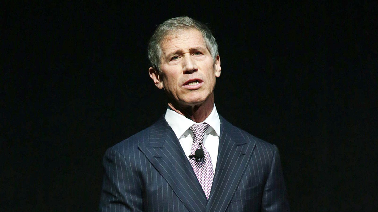 Lionsgate CEO Jon Feltheimer speaking at a corporate event in a pinstripe suit