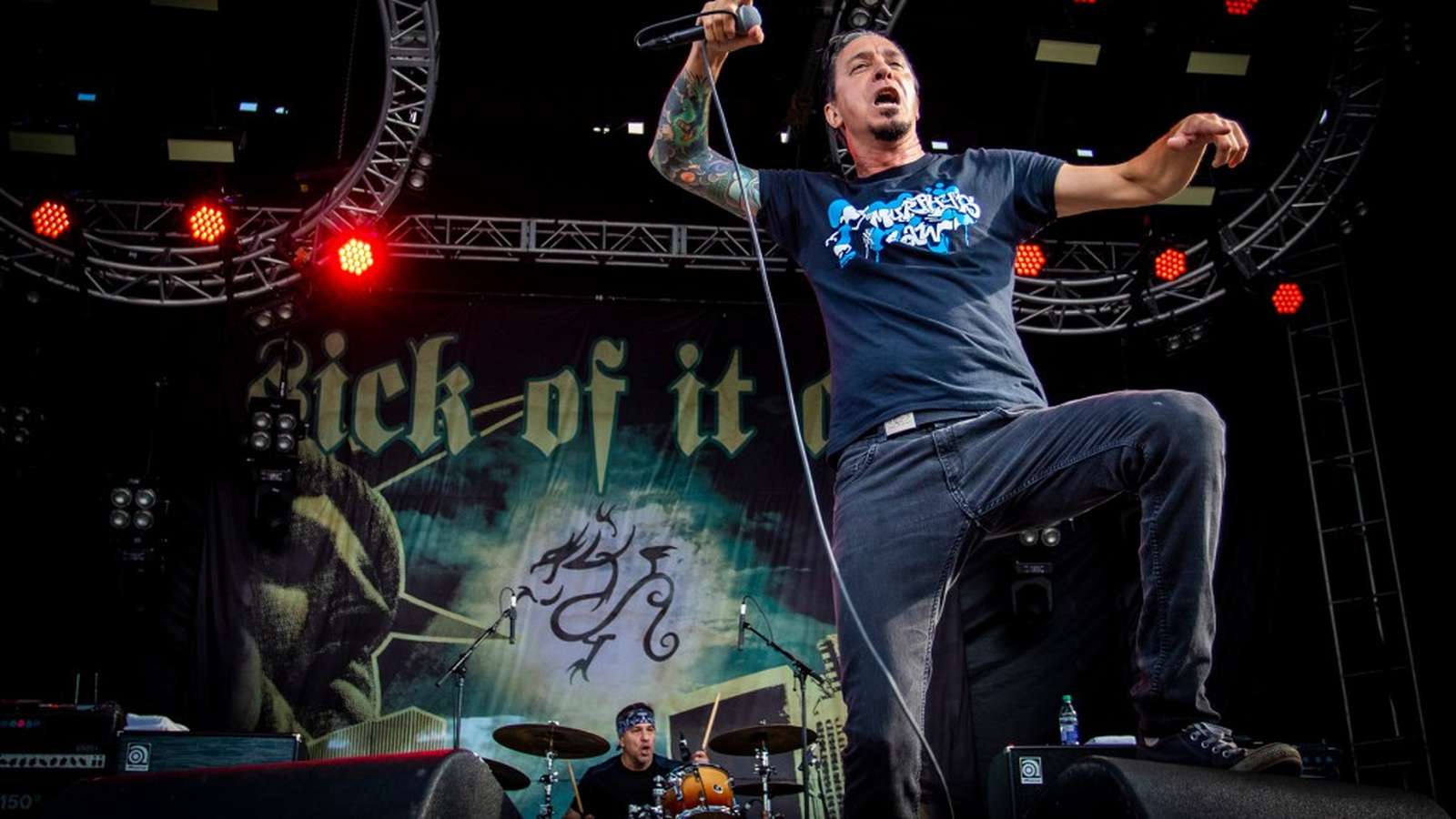 Lou Koller singing on stage with Sick of It All band banner behind