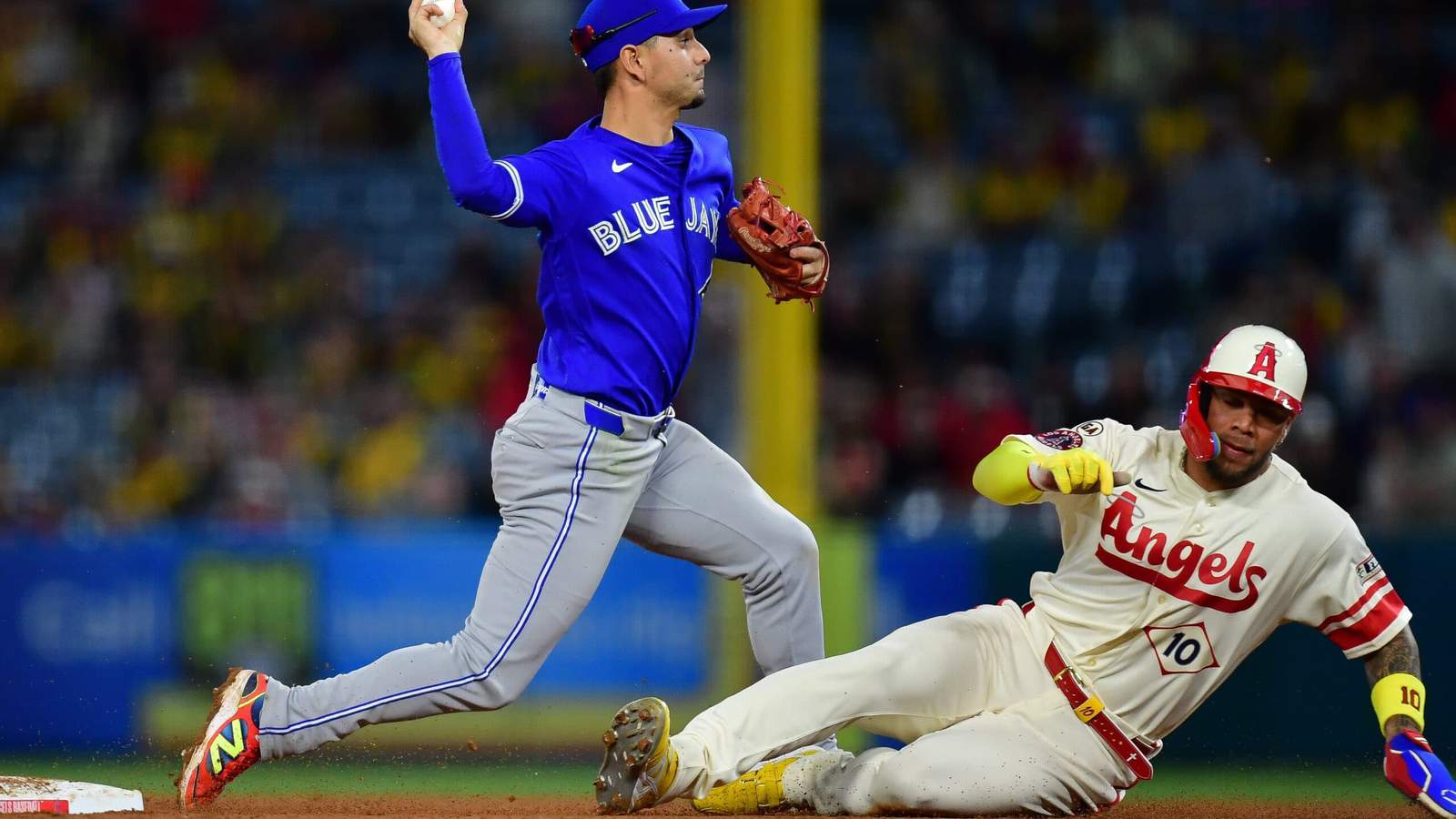 Toronto Blue Jays pitcher Louis Varland throwing a baseball while an Angels runner slides