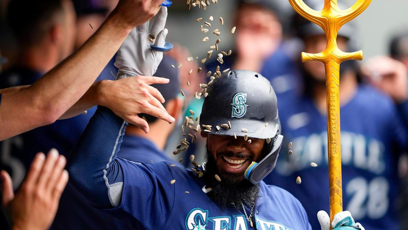 A Seattle Mariners baseball player smiling while being showered with sunflower seeds in celebration