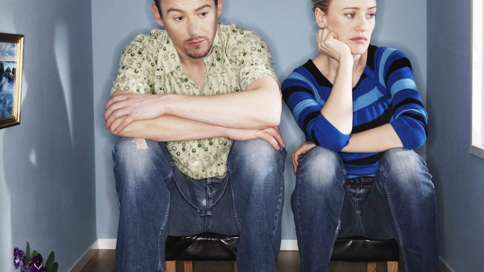 A man and woman sitting apart in a small room looking unhappy and distant