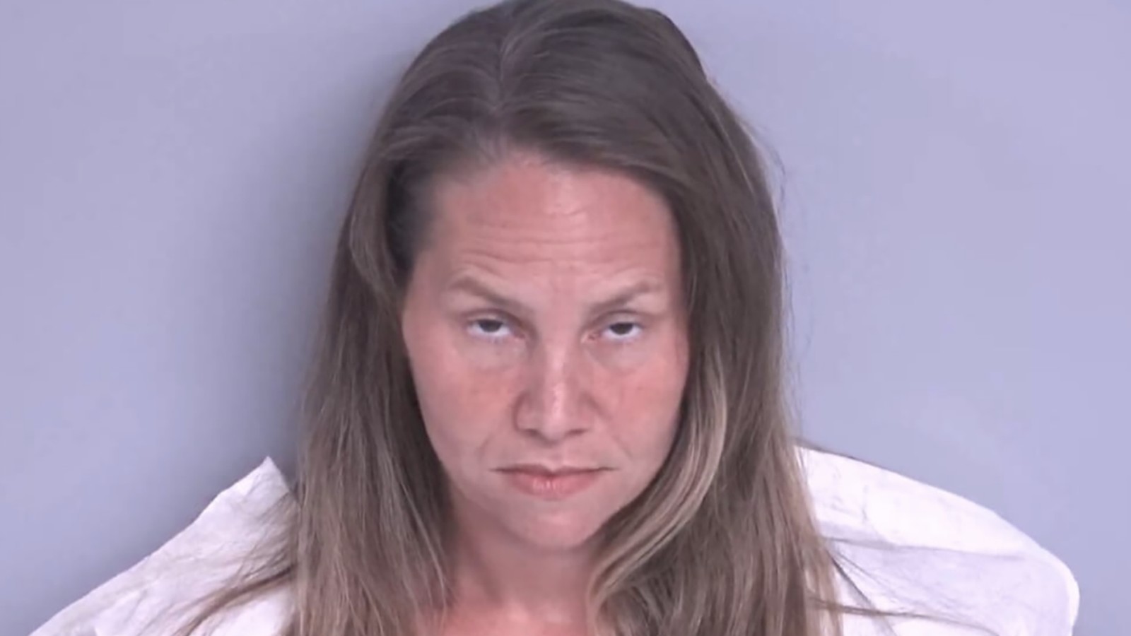 Mindy Osteen with long brown hair in a standard police booking mugshot photo