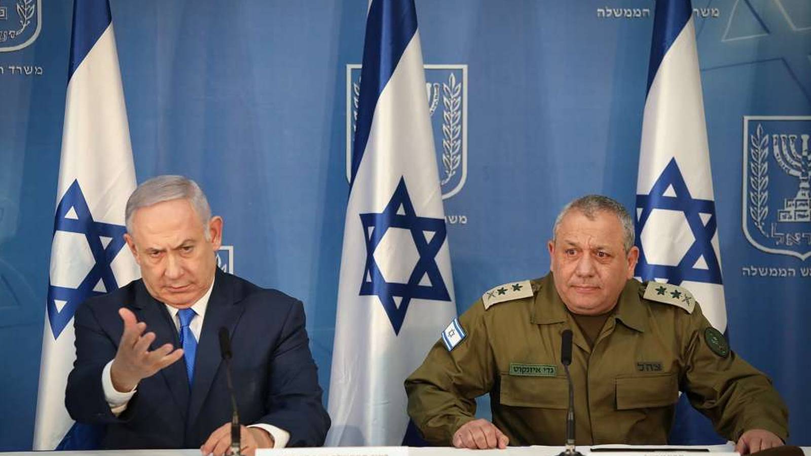 Benjamin Netanyahu and Gadi Eisenkot sitting at a table with Israeli flags behind them