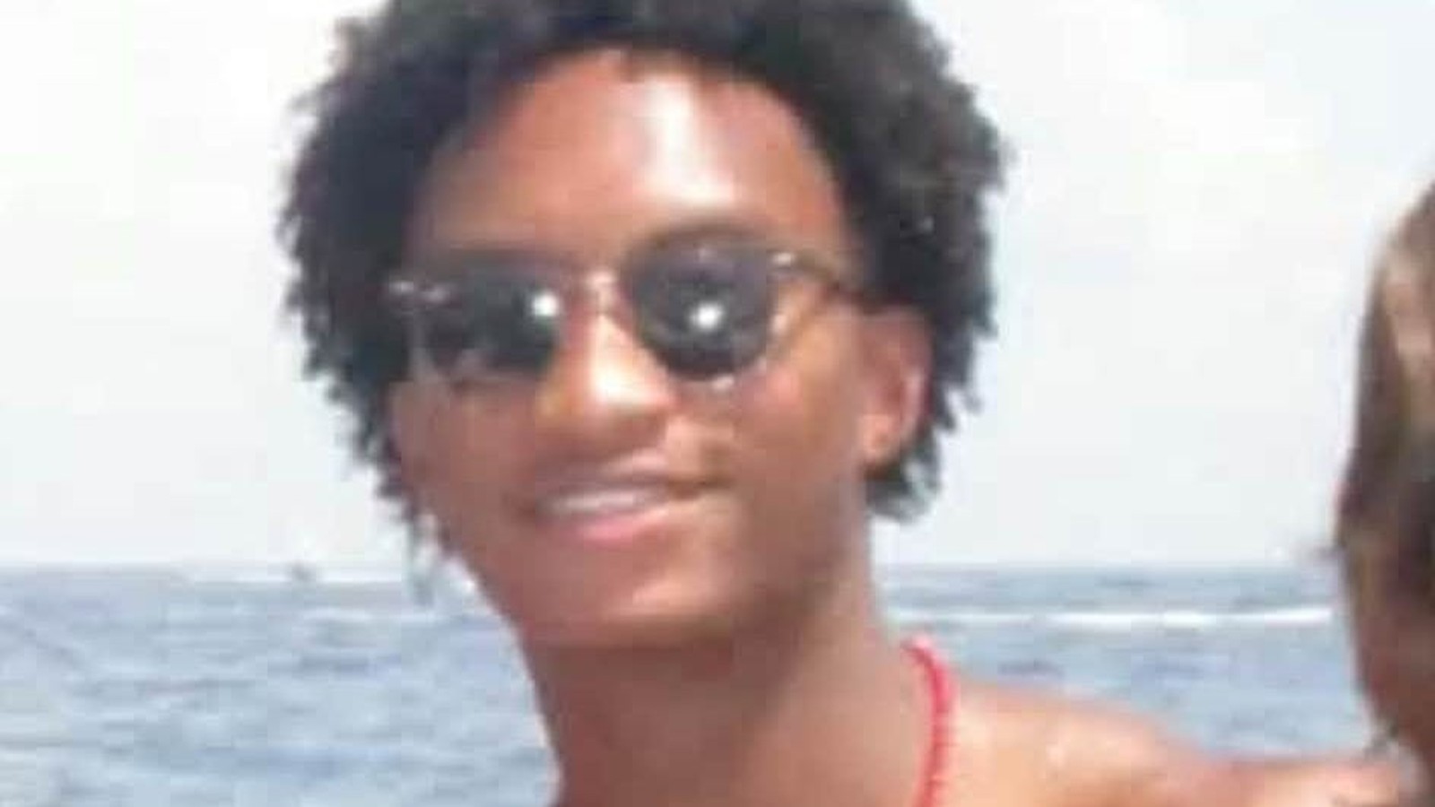 A portrait of Nolan Wells wearing sunglasses with the ocean in the background