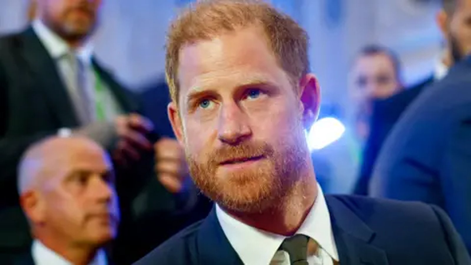 Prince Harry with a ginger beard wearing a dark suit at an event