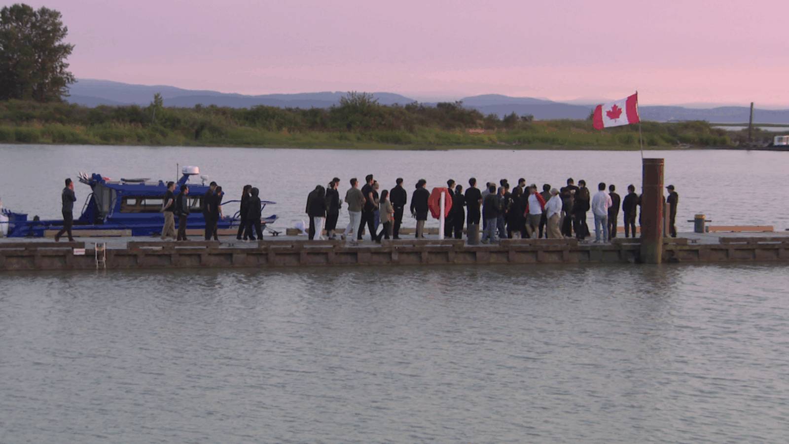 A group of people standing on a dock near a boat for a memorial service