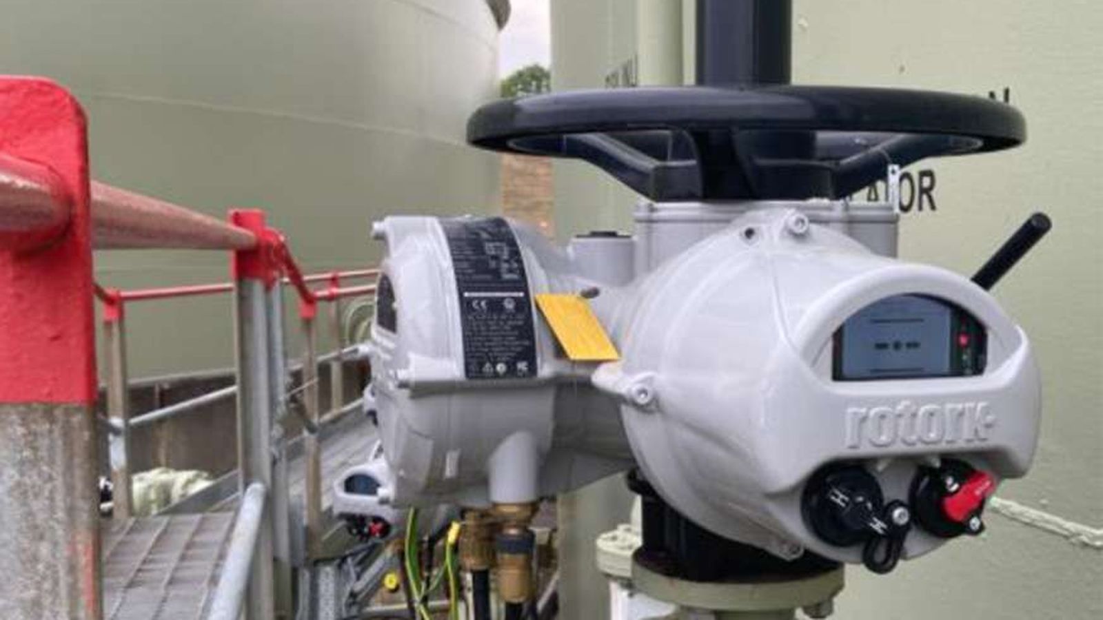 A grey Rotork industrial valve actuator installed on a large storage tank facility