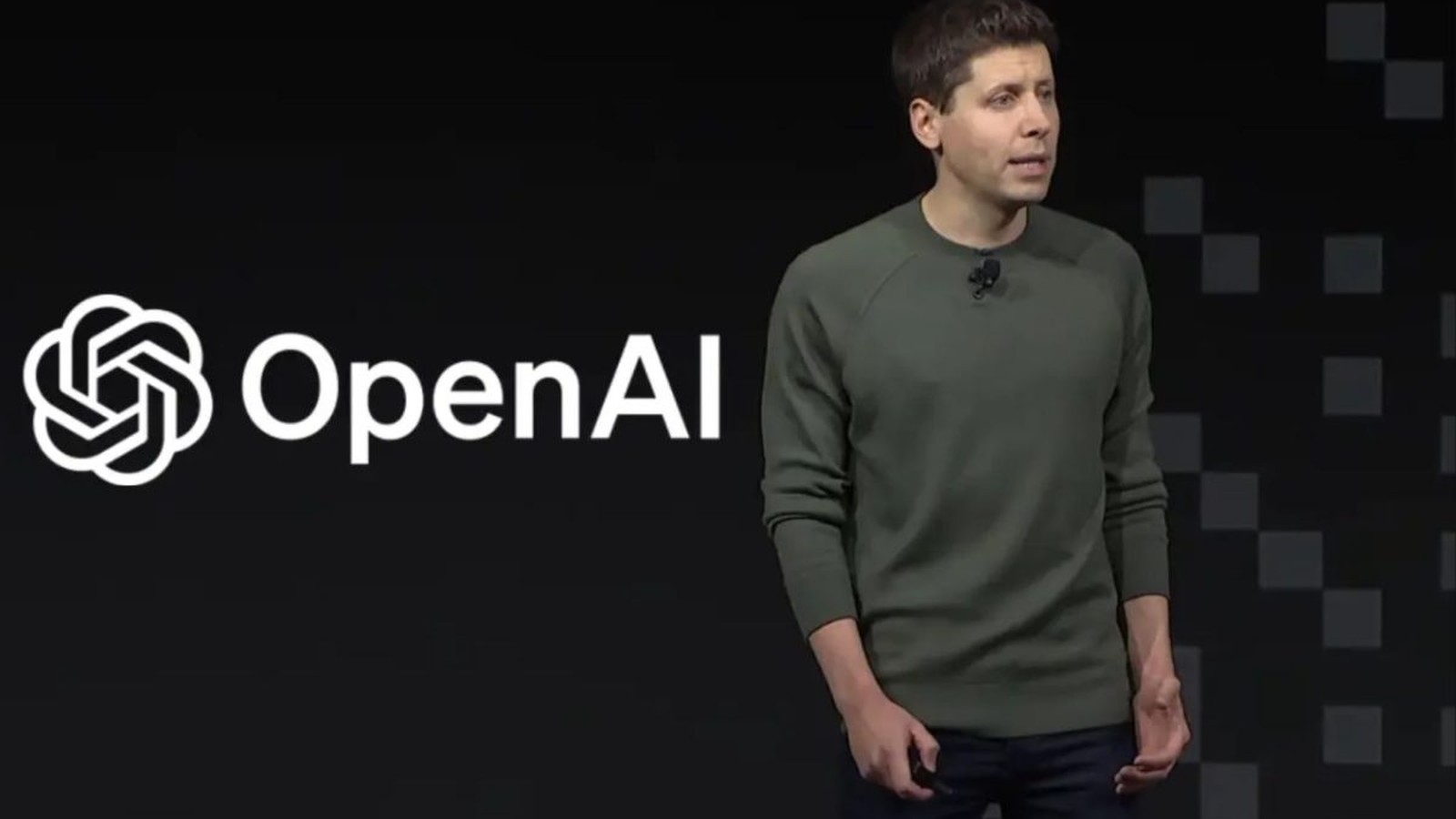 Sam Altman standing on stage in front of a large OpenAI logo backdrop