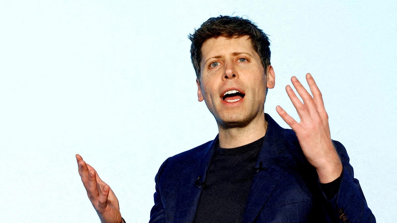 OpenAI CEO Sam Altman speaking with expressive hand gestures against a plain background