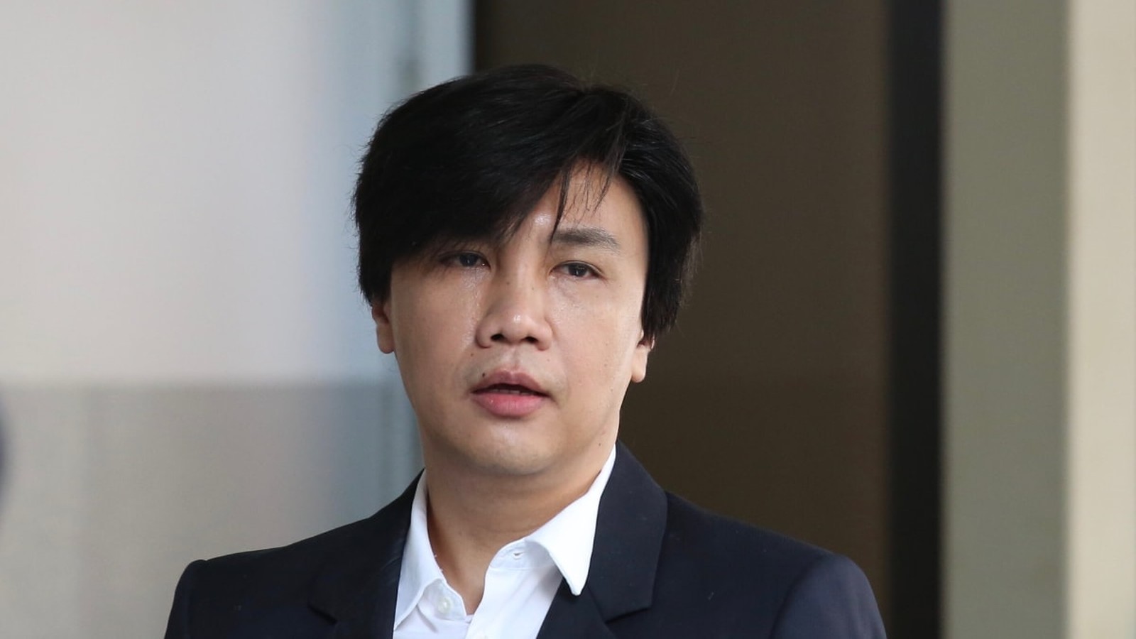 A portrait of Samuel Seow wearing a dark suit and white shirt