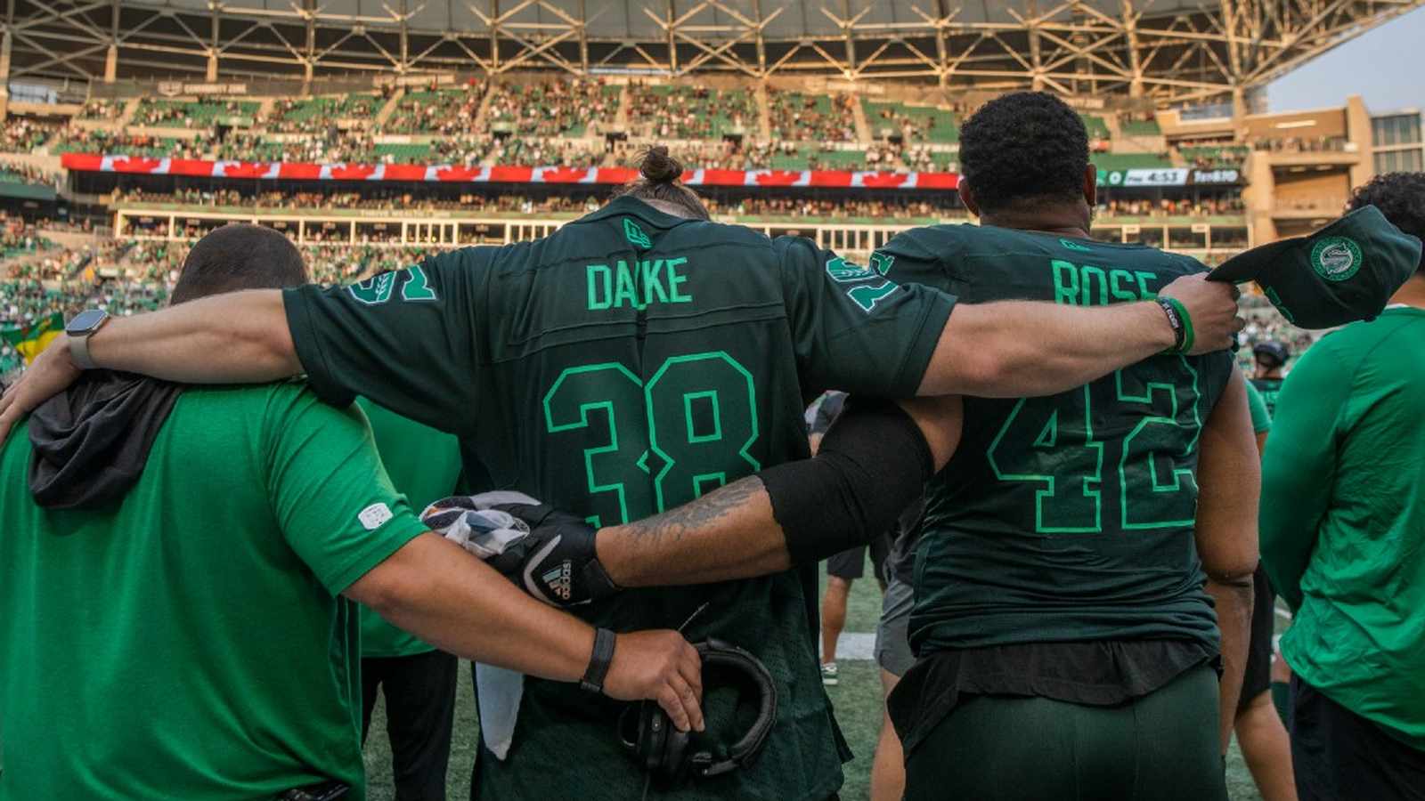 Saskatchewan Roughriders football players standing in a huddle during an emotional pre-game tribute
