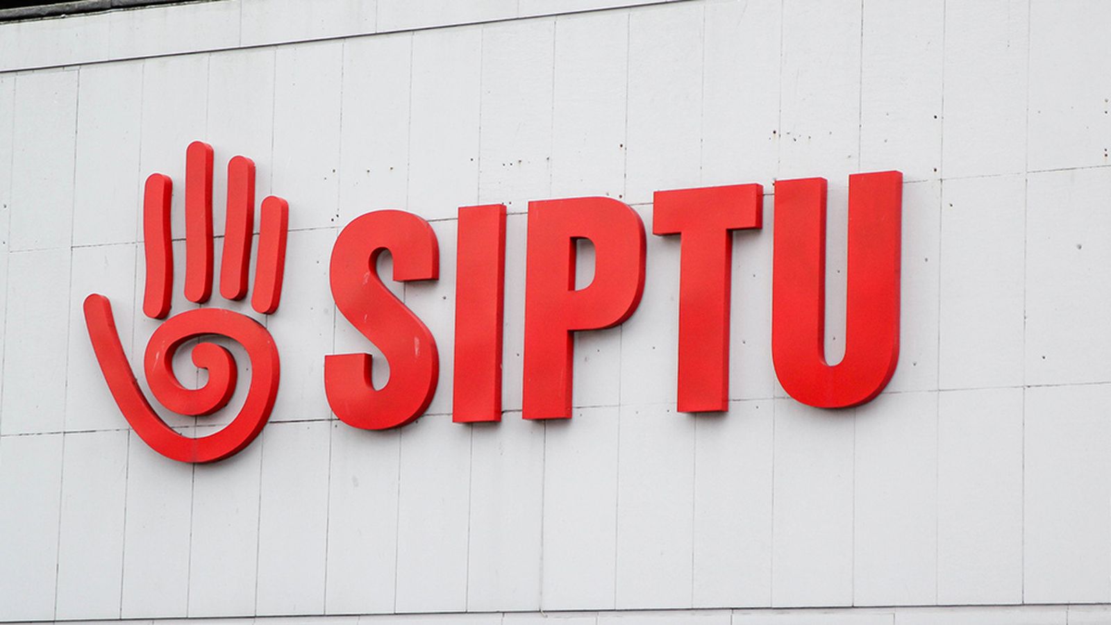The red SIPTU logo and text mounted on a white building exterior wall