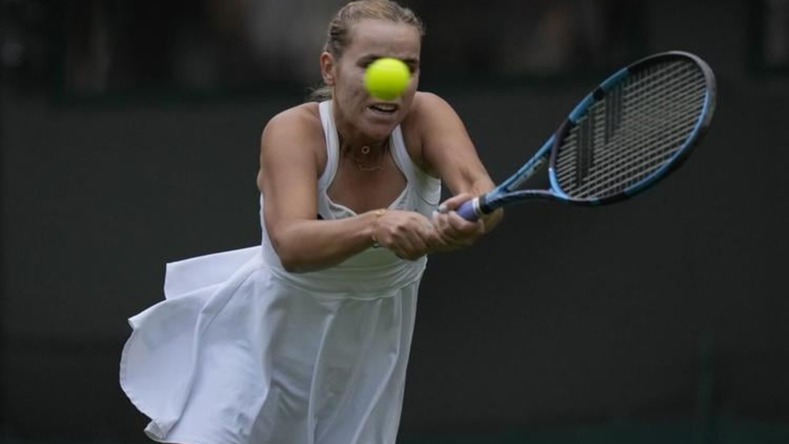 Sofia Kenin wearing a white tennis dress hitting a forehand during a match