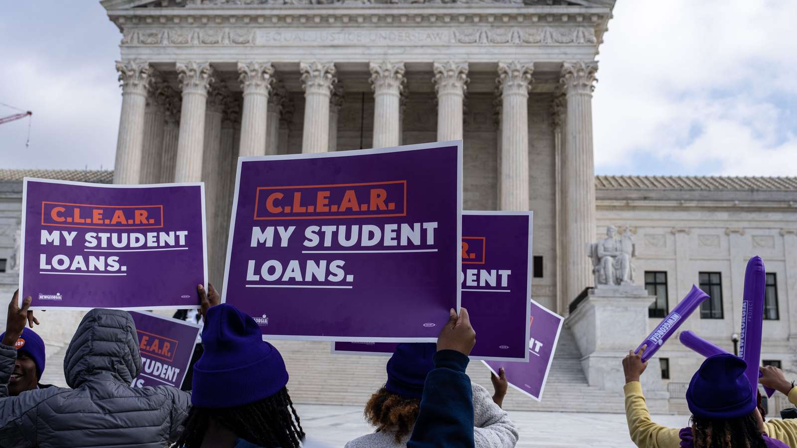 Protesters holding purple signs that say Clear My Student Loans at the Supreme Court