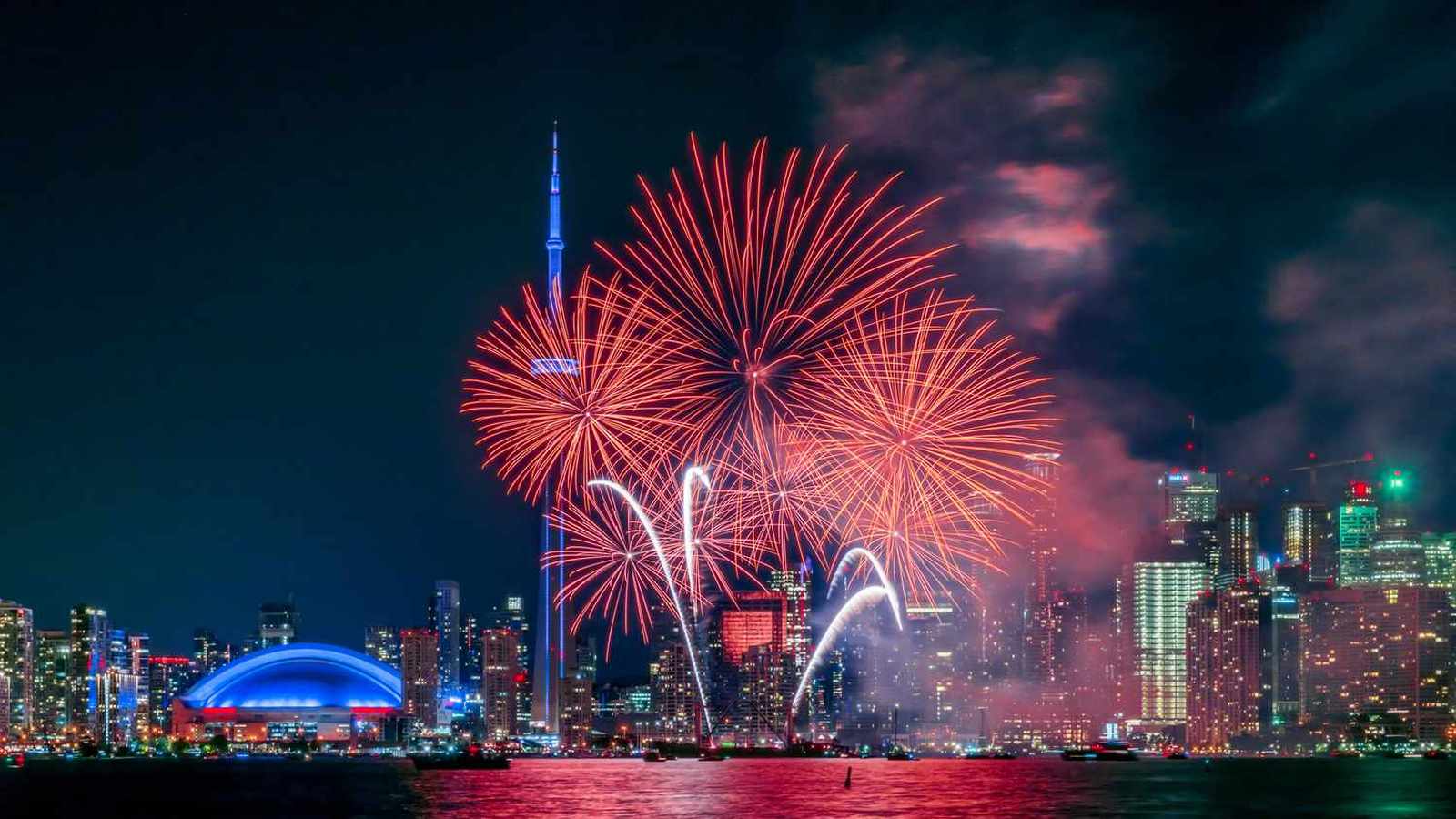 Bright red fireworks exploding over the Toronto skyline and CN Tower at night