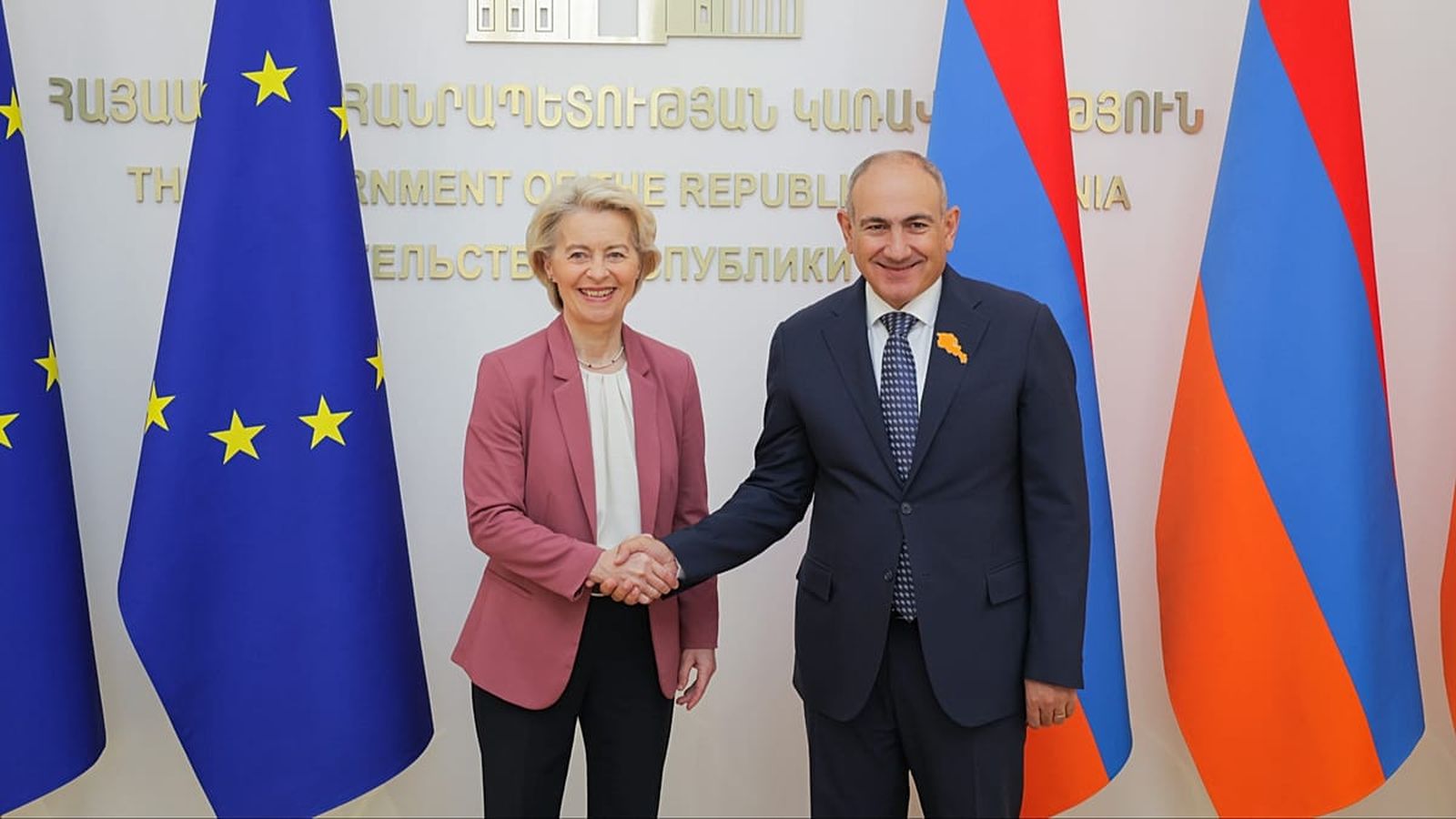 Ursula von der Leyen and Nikol Pashinyan shaking hands in front of flags
