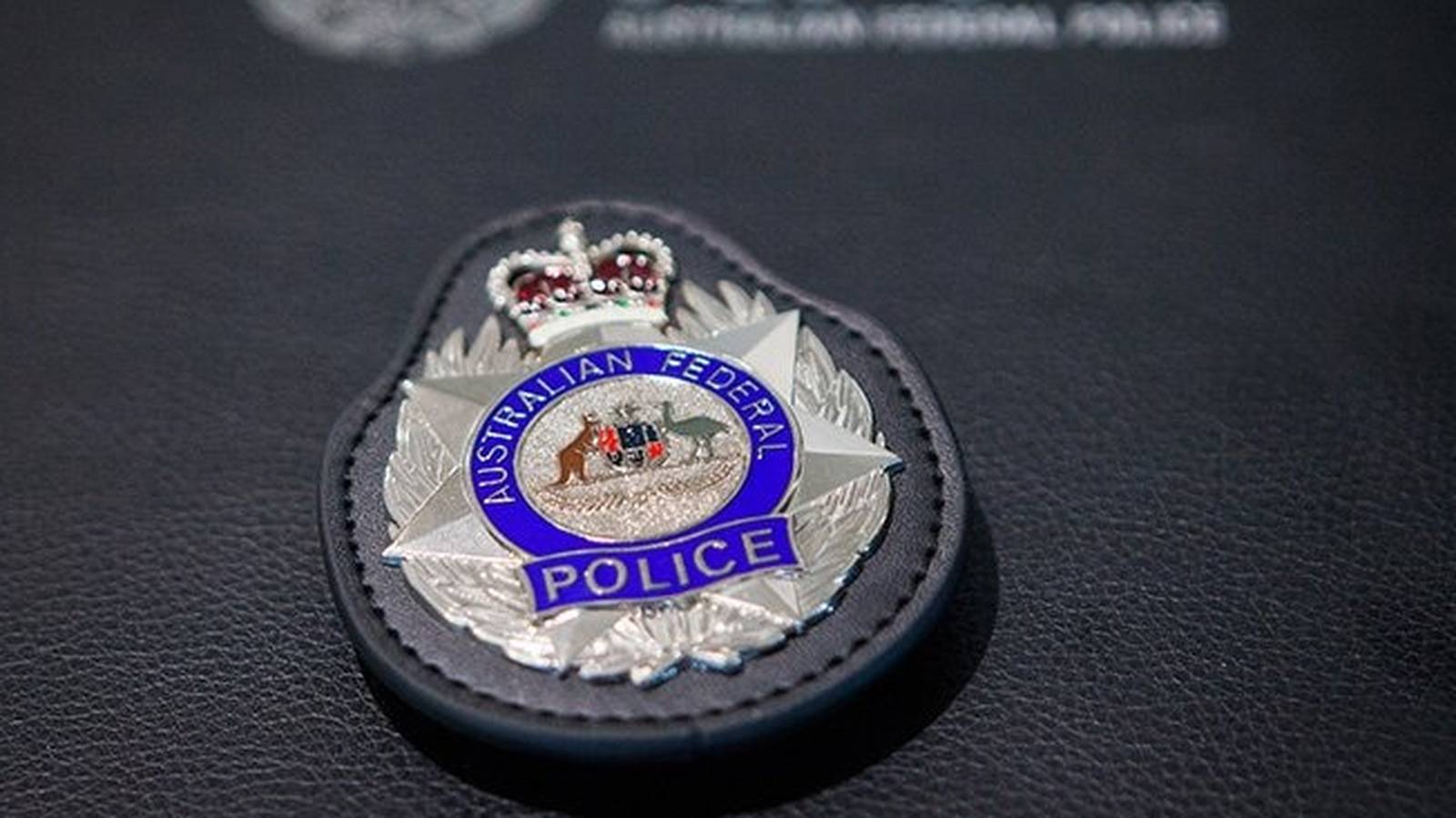 Close up of an Australian Federal Police badge resting on a black leather surface