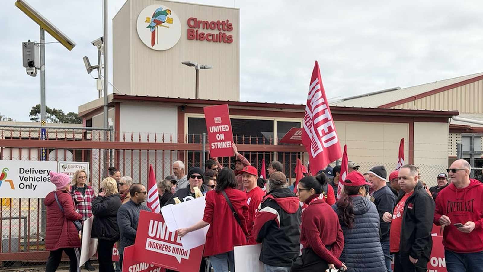 Arnotts factory workers holding strike signs and union flags outside the Adelaide facility