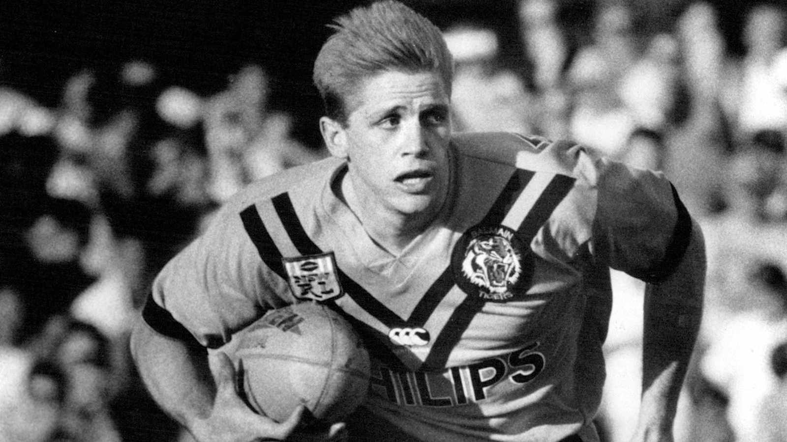 Young Brian Smith running with a rugby ball in a Balmain Tigers jersey