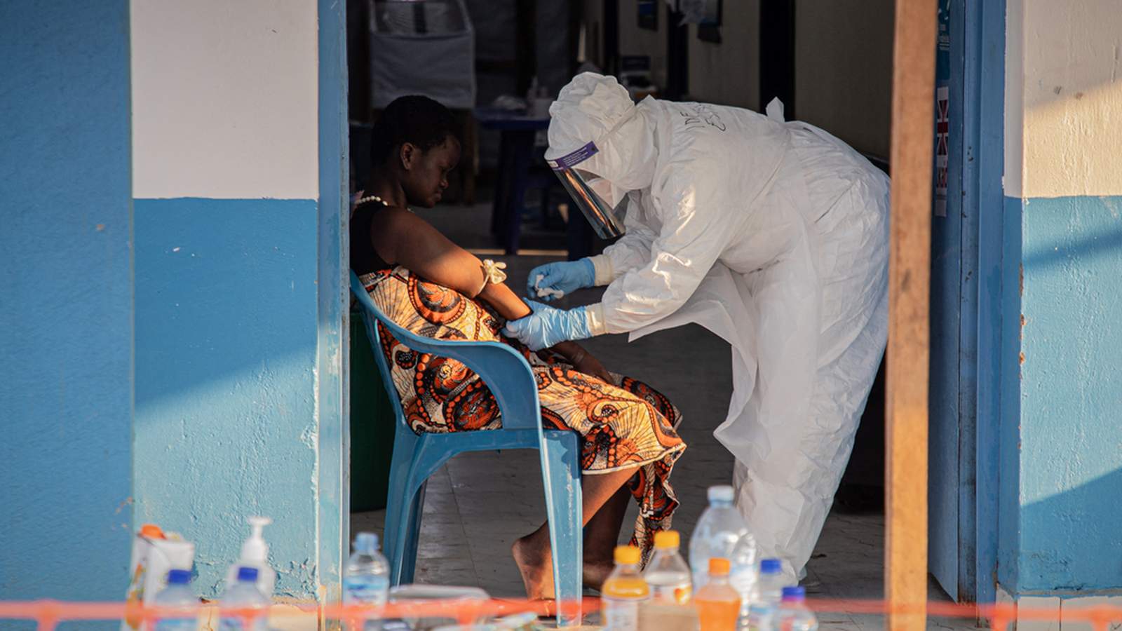 A healthcare worker in full protective gear treats a patient in the DRC