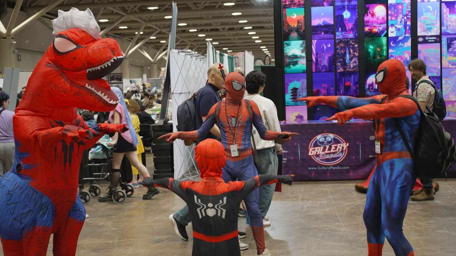 Multiple people dressed in Spider-Man and dinosaur costumes posing at a convention center