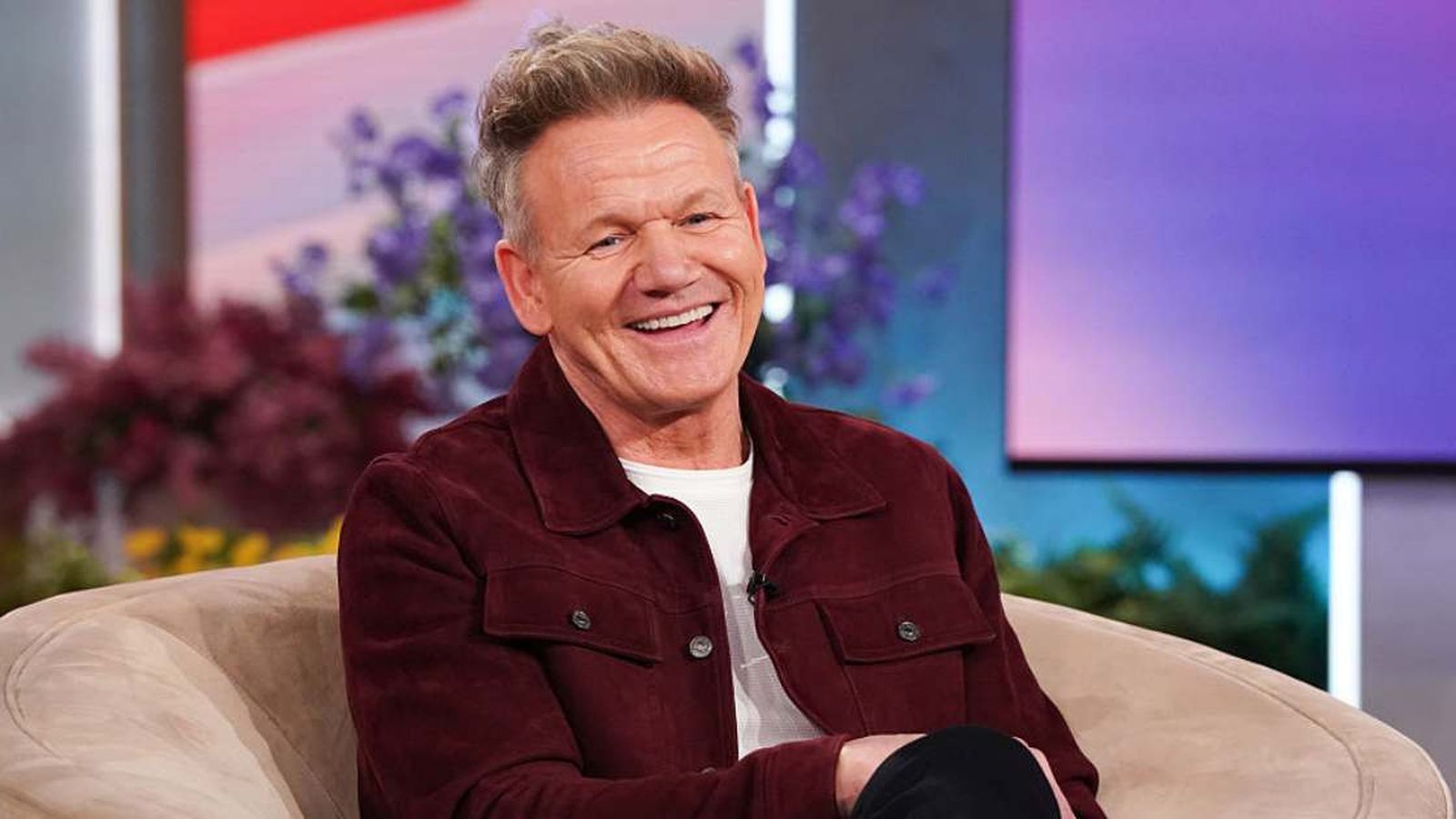 Celebrity chef Gordon Ramsay smiling while sitting in a chair during a television interview