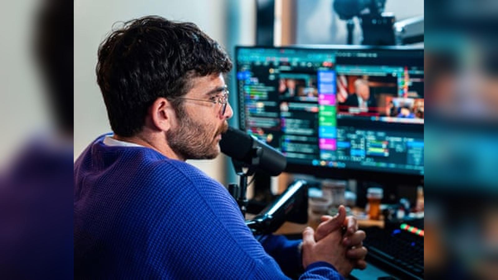 Hasan Piker wearing a blue sweater while streaming political commentary in front of monitors