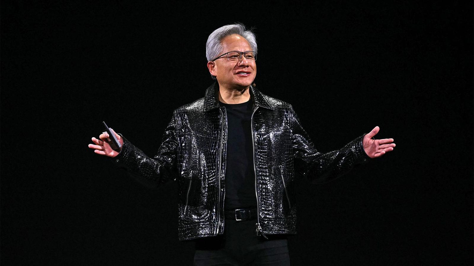 Nvidia CEO Jensen Huang wearing a black leather jacket speaking on a dark stage