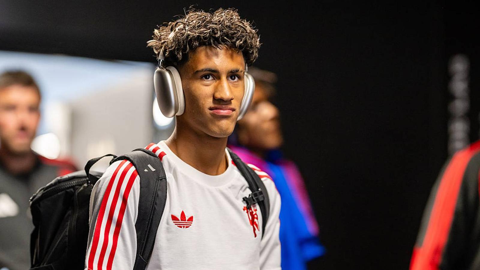 Young footballer JJ Gabriel wearing headphones and a white training top arriving at stadium
