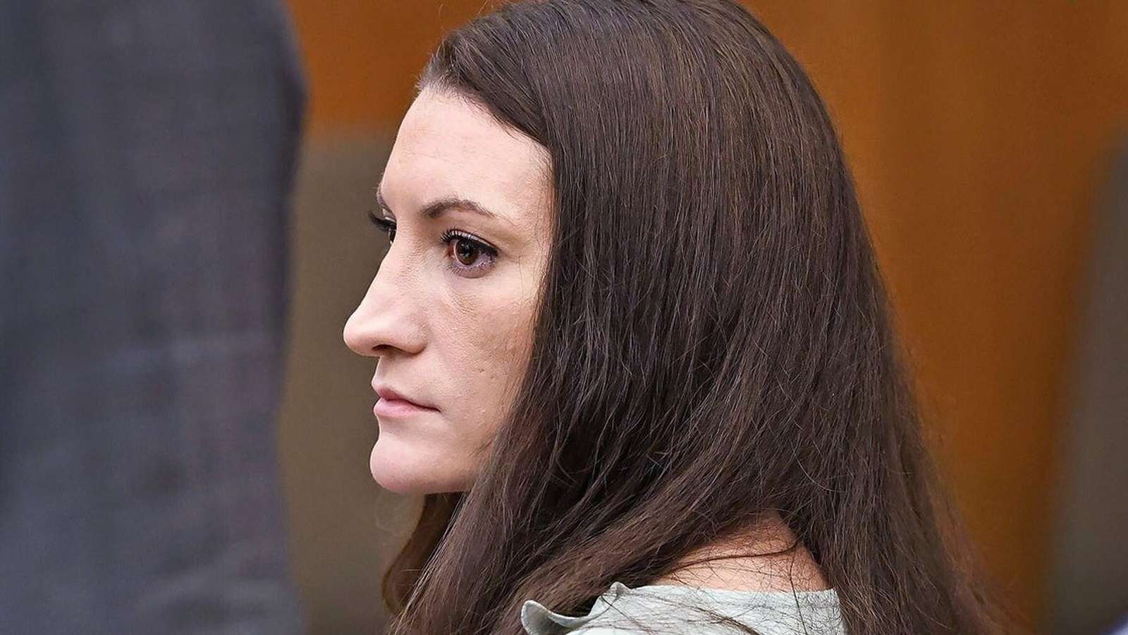 Lindsay Clancy with long brown hair looking to the side in a courtroom