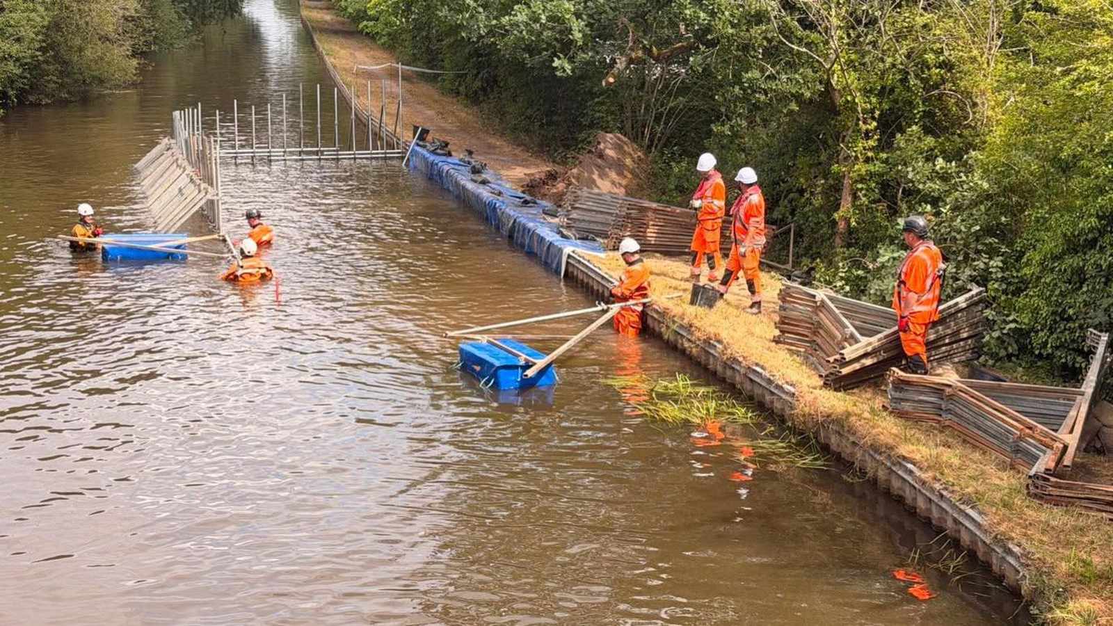 Construction workers in orange high-visibility gear repairing a breach on the Llangollen Canal