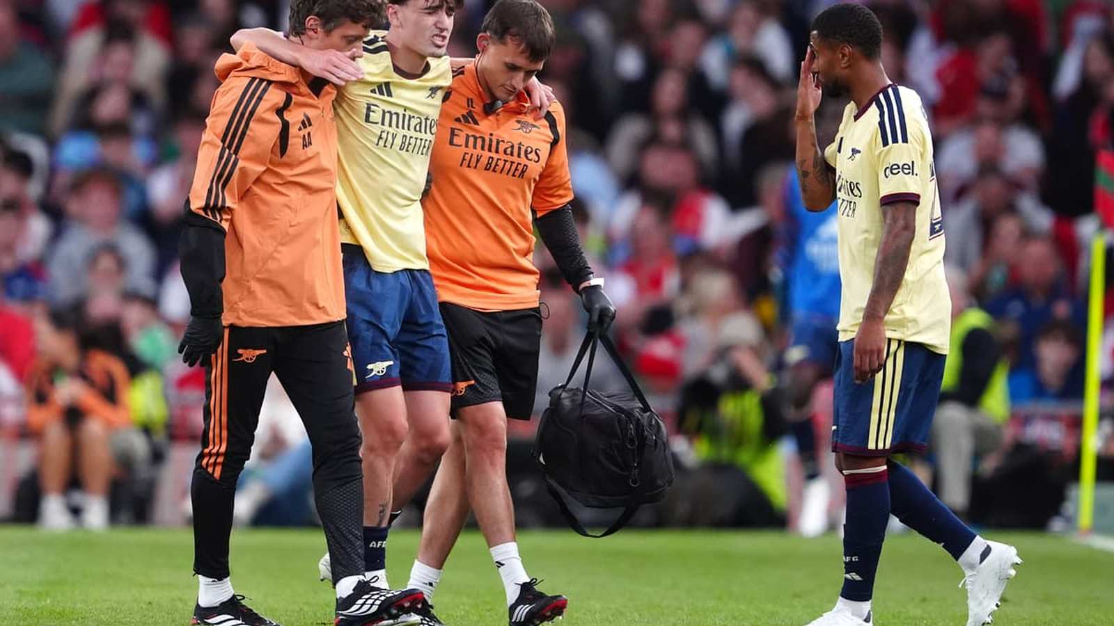 Arsenal player Louie Copley being helped off the pitch by medical staff after injury