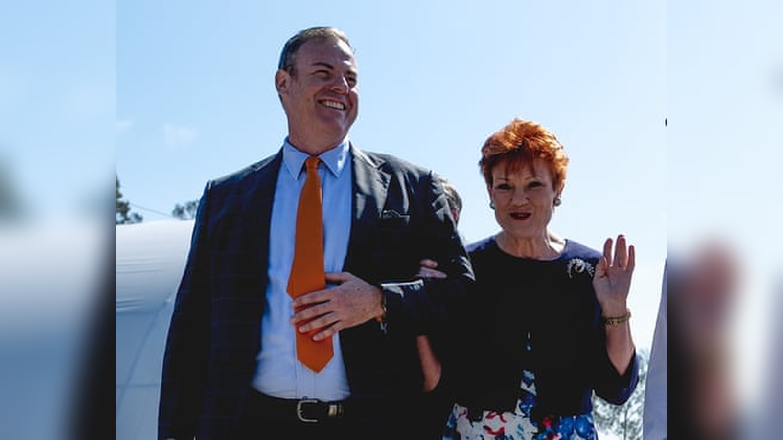 Mike Newman and Pauline Hanson smiling together during a public political appearance outdoors